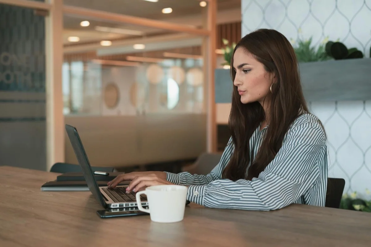 Professionista concentrata al lavoro su laptop in ufficio moderno