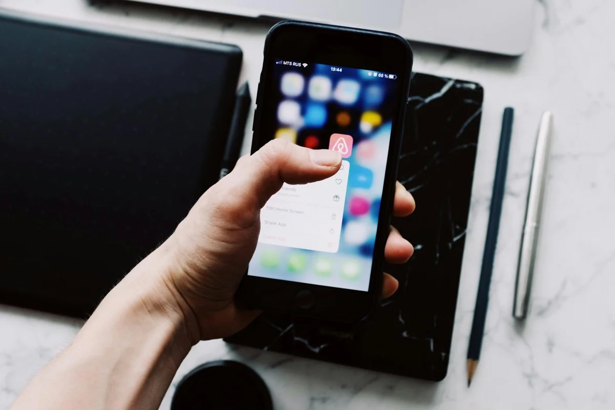 Persona tiene smartphone con icone app, accesso multi-device all'area riservata