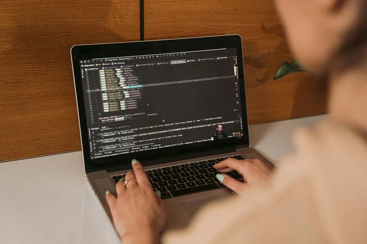 Donna che lavora al codice su laptop in ufficio moderno, implementazione sicurezza tecnica
